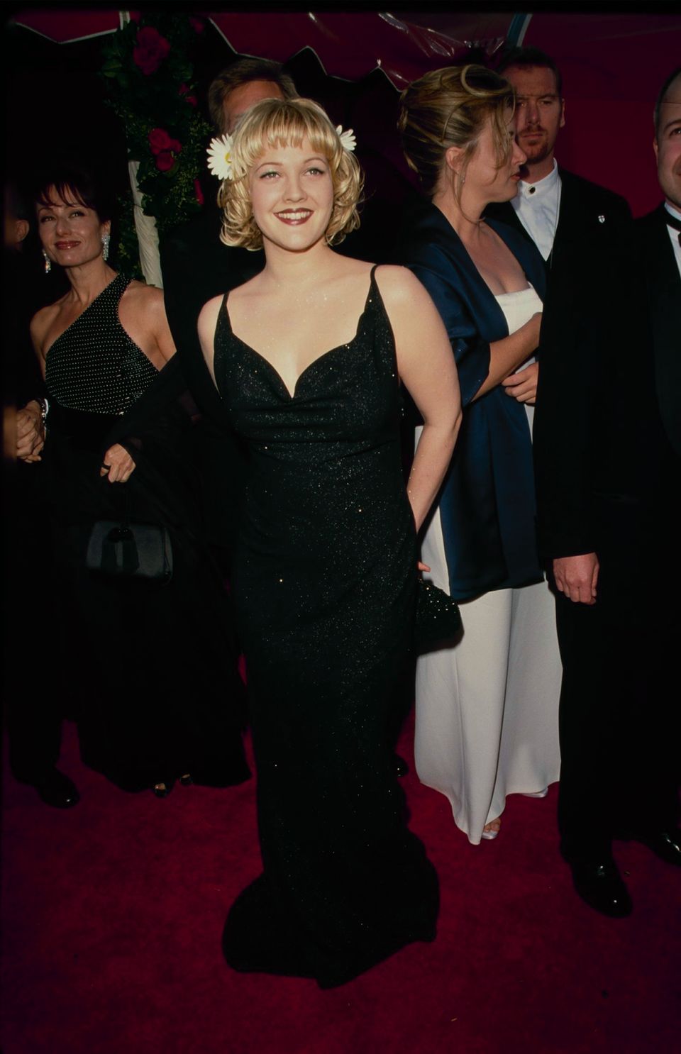 Drew Barrymore mặc đầm dạ hội đen và cài hoa lên tóc trên thảm đỏ Oscar năm 1998