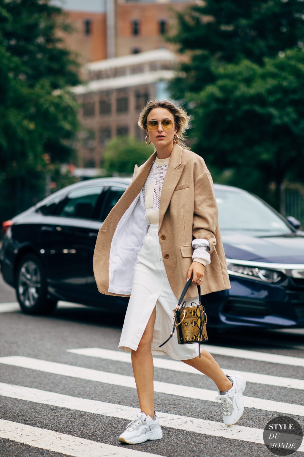 Rebecca Laurey diện blazer màu beige chân váy trắng kính mát tuần lễ thời trang new york